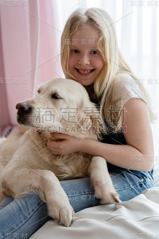 关心和爱护宠物。十几岁的女孩在家里与一只金毛猎犬大狗拥抱