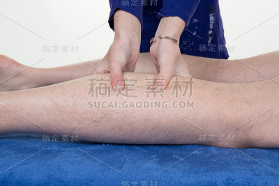 用手按摩人的小腿肌肉。治疗师在男性腿上施加压力。