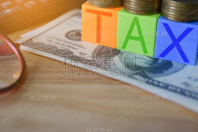 增长的税收-特写彩色块与税和钱在桌子上-税收概念