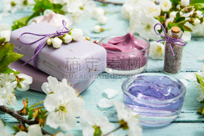 蓝色的木桌上放着化妆品和樱花