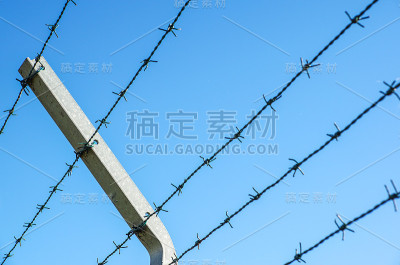 盘绕的剃须刀线和锋利的钢倒钩在铁丝网周围的围栏上，确保安全