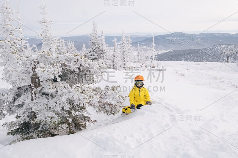 孩子滑雪板座位附近的雪覆盖的冷杉树在滑雪胜地的山顶