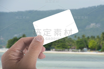 在海滩背景上手持空白卡片