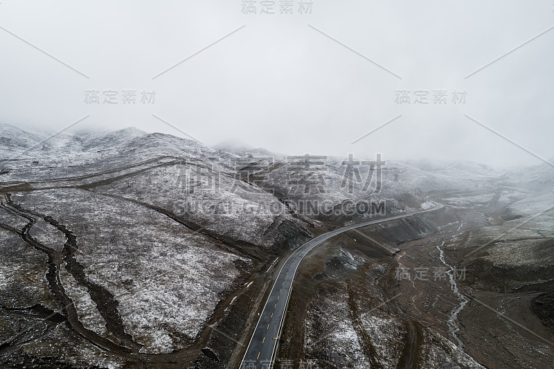 蜿蜒穿过被雪山环绕的山谷的乡村道路