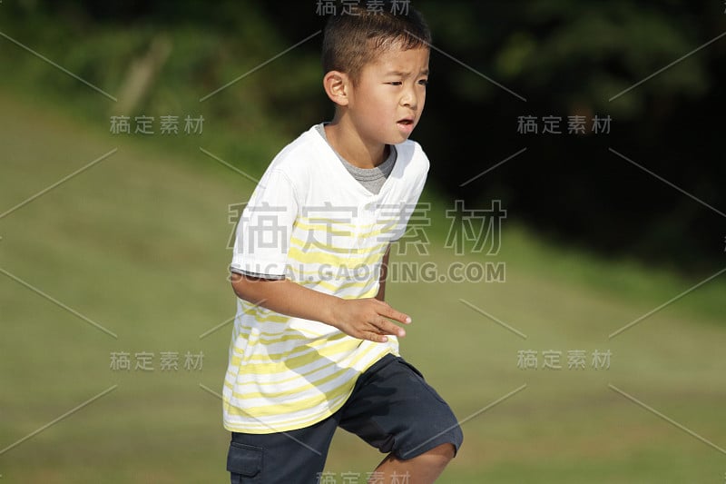 日本男孩在草地上跑步(小学二年级)