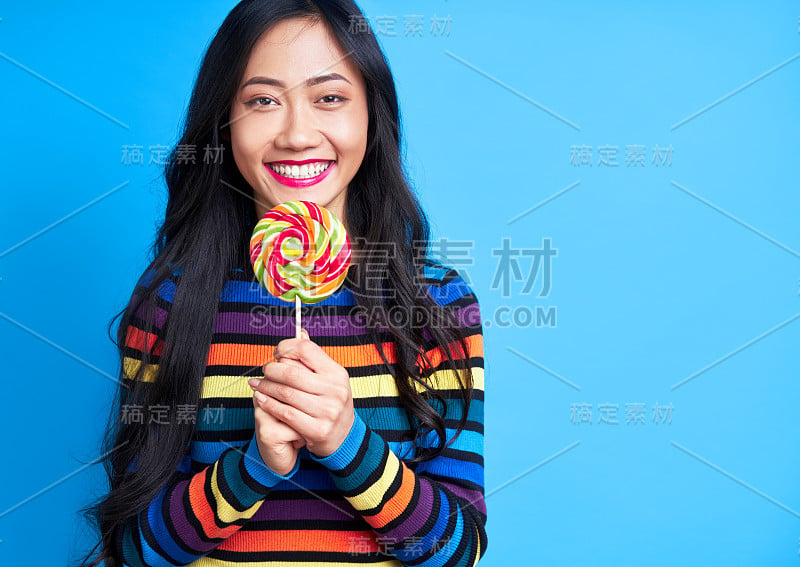 幸福美丽的女人与彩色的棒棒糖孤立在蓝色的背景