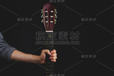 手握着吉他。黑色背景上的原声乐器