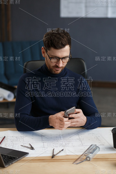 年轻人微笑着用智能手机。快乐的商人使用手机应用程序，发短信，浏览互联网，看智能手机。年轻人使用移动设