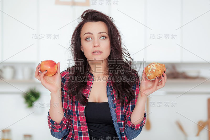 饮食。节食的概念。健康食品。美丽的年轻女子选择水果和糖果。减肥