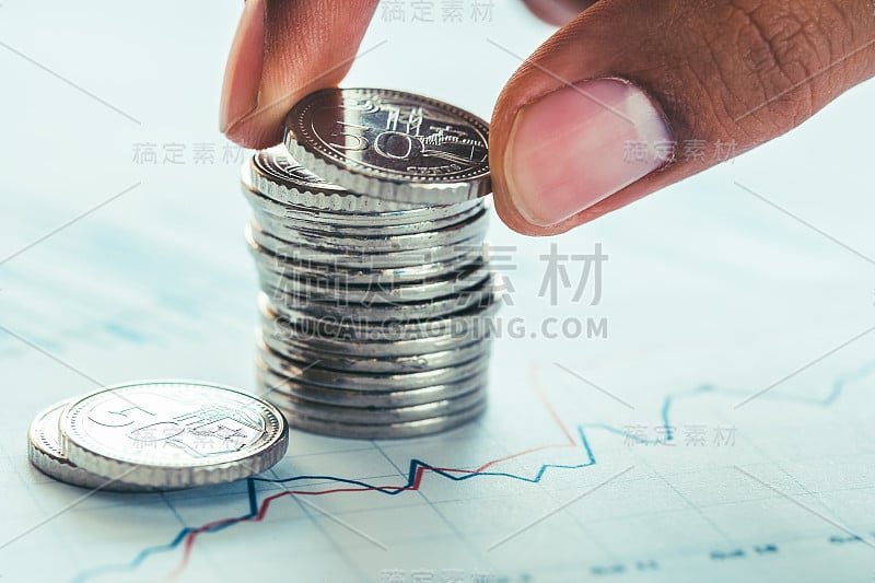 人的手指拿着硬币在堆叠硬币