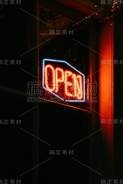 红色的开放霓虹灯在夜晚闪闪发光。