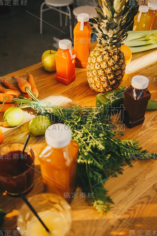 健康新鲜排毒果汁和食品理念。不同的蔬菜和果汁装在塑料瓶里放在木桌上。室内