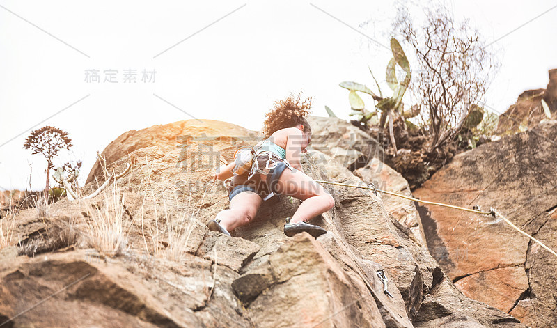 年轻女子攀登一个峡谷的岩壁-强壮的登山者训练户外-旅行，肾上腺素和极端危险的运动概念-集中在她的头部