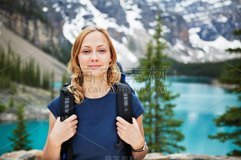 女徒步旅行者与她的背包反对风景