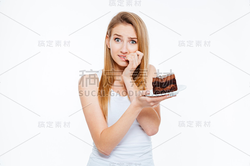 怀疑的女人在节食思考和拿着一块蛋糕