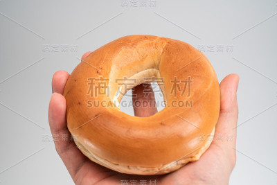圈面包(百吉饼)在手孤立的白色