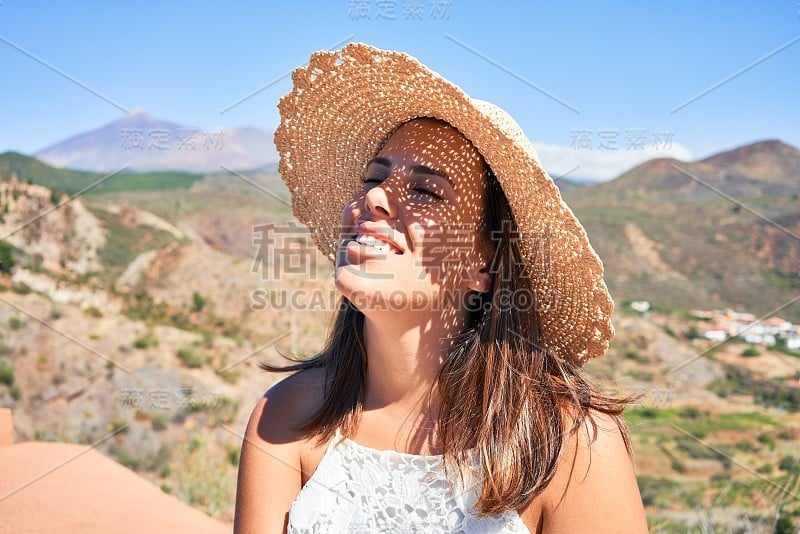 年轻美丽的女子在山上享受着暑假的风景，旅行者女孩笑得很开心