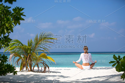 冥想瑜伽女人在宁静的热带海滩冥想。女孩放松在荷花姿势在平静的禅意时刻在海水