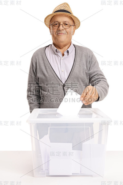 一位老人把一张选票放进一个盒子里，看着摄像机