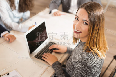 美丽的年轻女商人工作在她的电脑和微笑