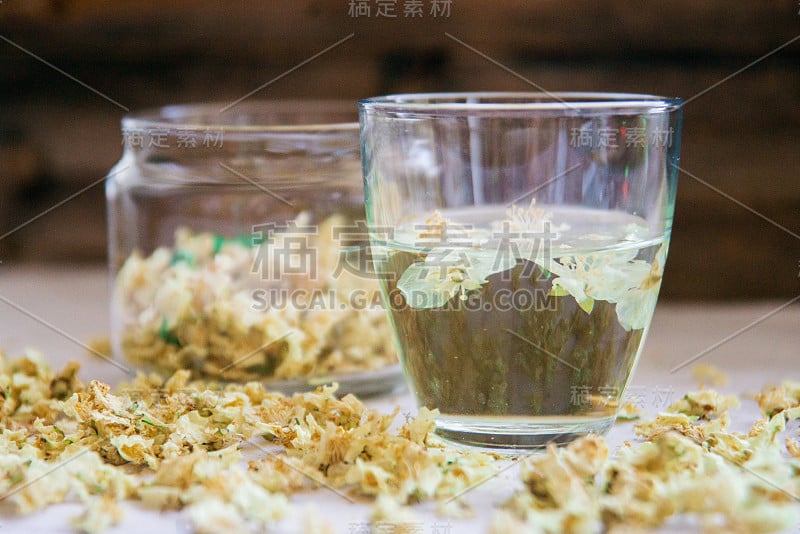 绿色背景木桌上的茉莉花绿茶杯和茶壶