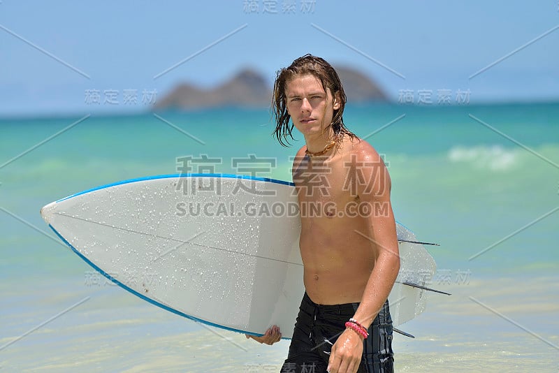 年轻的白人男性在夏威夷的海滩上拿着冲浪板