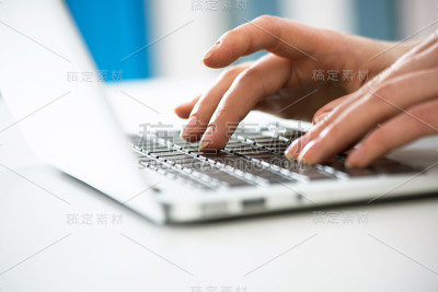 在笔记本电脑上打字的女商人的手的特写。
