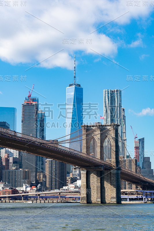 东河上悬挂着美国国旗的布鲁克林大桥和曼哈顿下城的纽约市天际线