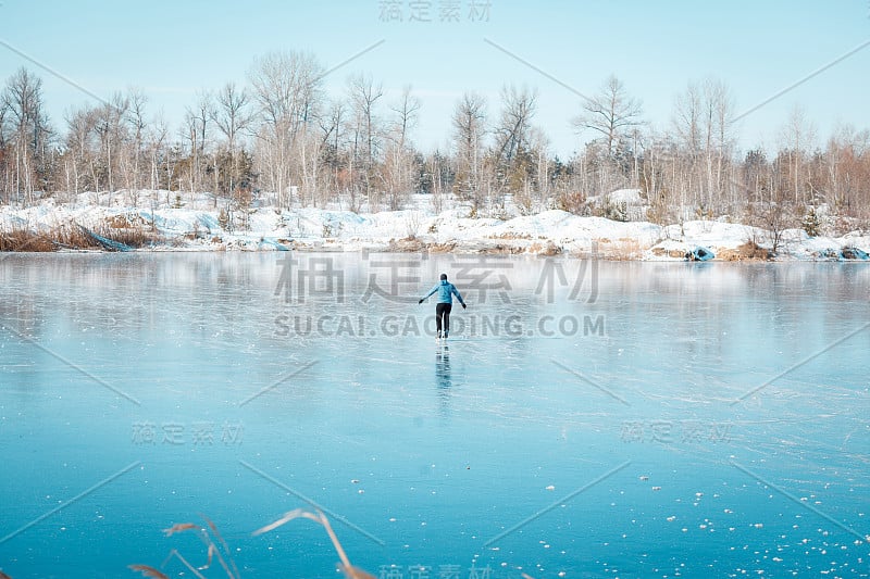 一个年轻人在结冰的湖面上溜冰。