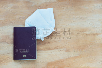 准备护照、N95口罩等境外黄昏防护和病毒防护的旅行用品的顶级层压板木桌/边框一侧为复印空间