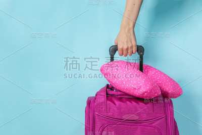旅行概念-粉红色手提箱前面的蓝色背景