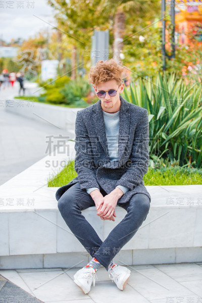 英俊的男孩在自然背景的相机上摆姿势。