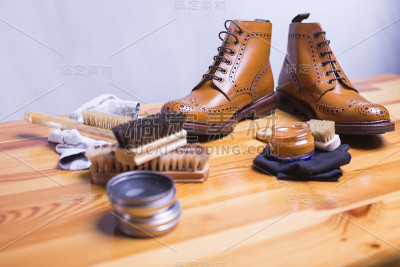 鞋的想法和概念。特写Premium Tan Brogue皮靴与一套清洁配件，蜡和布。水平的作文