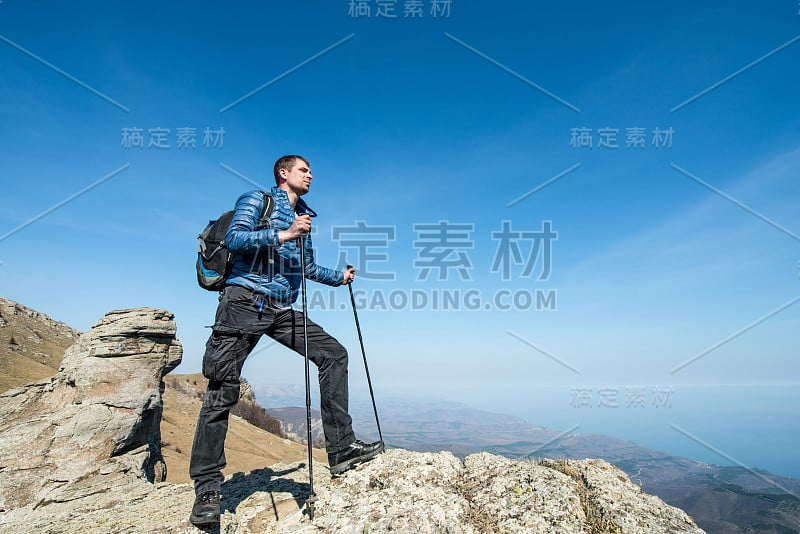 在山顶上背着背包拿着拐杖的旅行者