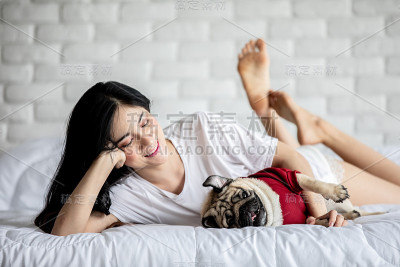 年轻女子玩她的狗和微笑与哈巴狗品种