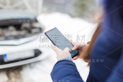 交通、车辆和冬季概念。妇女使用黑屏手机打电话或短信汽车机械道路援助服务。