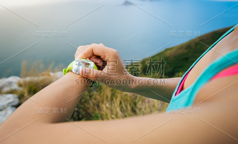 年轻女子慢跑准备跑步设置运动智能手表。运动和健身户外海滨小径。