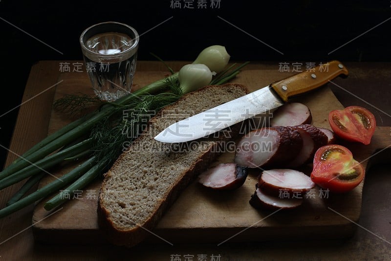 简单质朴的食物。香肠，西红柿，刀子和面包。