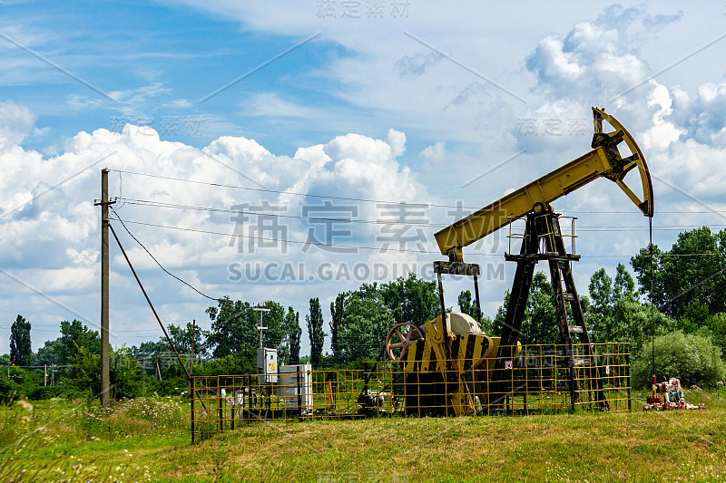 石油钻机在输电线和阴天中泵出原油。油田钻机的特写。钻机被金属栅栏围起来。美丽的山的风景。