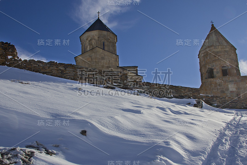 乔治亚州格盖蒂的圣三位一体教堂。教堂坐落在白雪覆盖的山峰中间，那是一个冬天的早晨，下着雪。