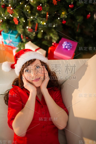 红头发的人戴着圣诞帽在沙发上放松圣诞节