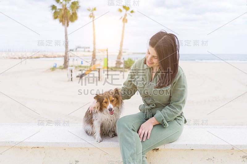 年轻漂亮的女人笑得很开心在海滩遛狗