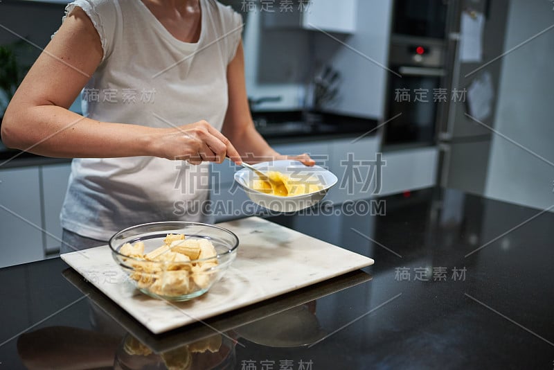 一个女人正在搅拌鸡蛋，准备做香蕉煎饼