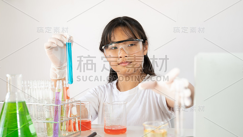 年轻可爱的女孩在安全眼镜和手套拿着一个化学烧瓶在现代实验室做一个科学家实验与孤立的白色背景的照片。