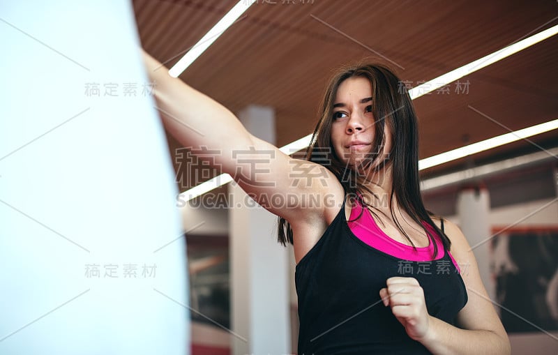 一个年轻女子在室内练习空手道。抄写空间。