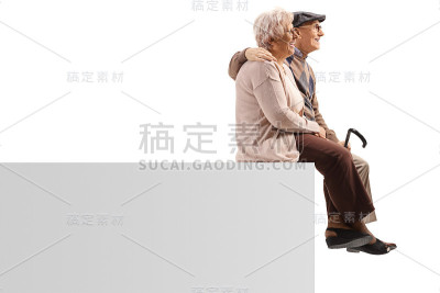 一对老年夫妇坐在一个空白面板上拥抱的侧面照片