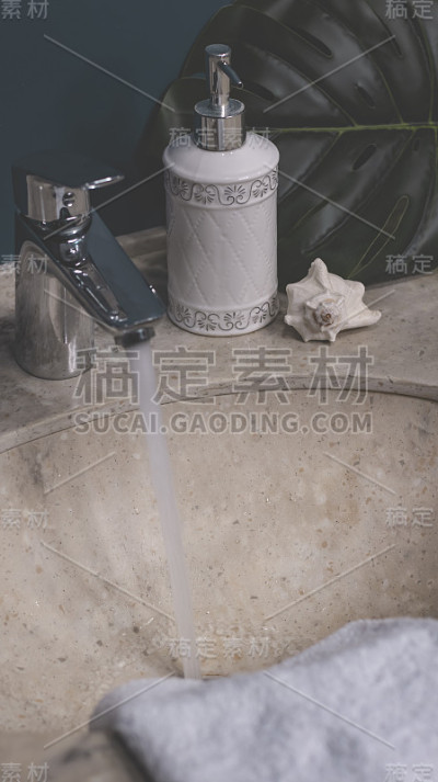 色彩新潮的浴室，洗涤区，卫生整洁。圆形金属镜，棉垫，耳棒，膏霜，液体肥皂在一个分配器。石材台面，白色