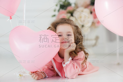 可爱的六岁女孩穿着粉红色的裙子，粉红色的气球在心形