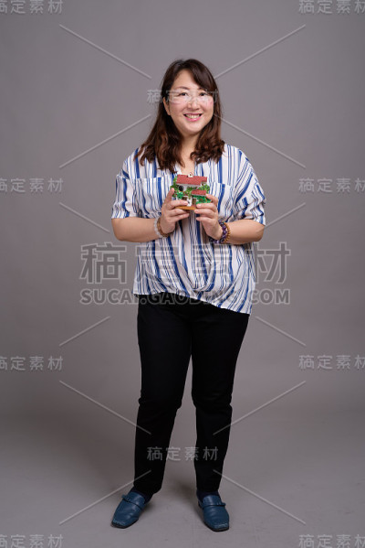 工作室拍摄的成熟美丽的亚洲女商人在灰色的背景