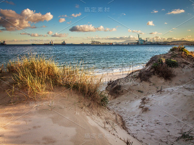 海滩和沙丘与海草和云与阿尔赫西拉斯港的背景